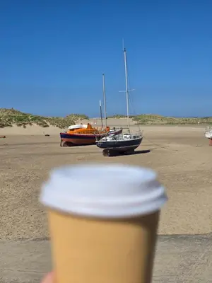 a cup of coffee with two boats on the beach at Seasalt Apartment in Barmouth