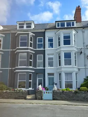 a white house with blue windows on a street at Seasalt Apartment in Barmouth