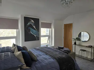 a bedroom with a bed with a blue comforter at Seasalt Apartment in Barmouth