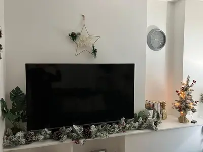 a flat screen tv sitting on a shelf with christmas decorations at Seasalt Apartment in Barmouth