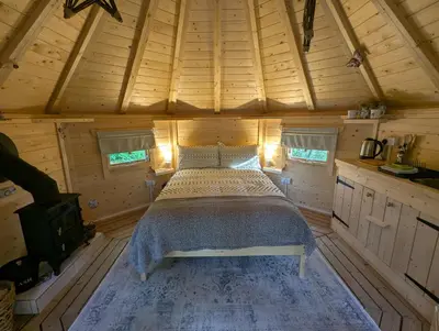 a bed in the center of a wooden cabin at Bluebell Hideaway in Llanfair Clydogau