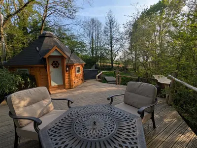 a deck with a table and chairs and a small cabin at Bluebell Hideaway in Llanfair Clydogau