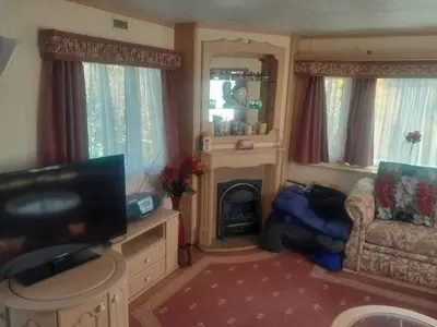 a living room with a television and a fireplace at 254 Bryn y Mor in Tywyn