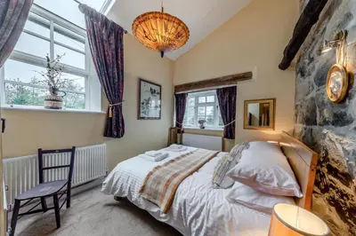 a bedroom with a bed and a stone wall at 4 Bed in Arthog oc-b31966 in Arthog