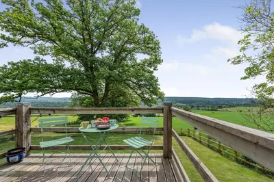a deck with chairs and a table and a view of a field at 1 Bed in Brynteg oc-g32079 in Llanwenog