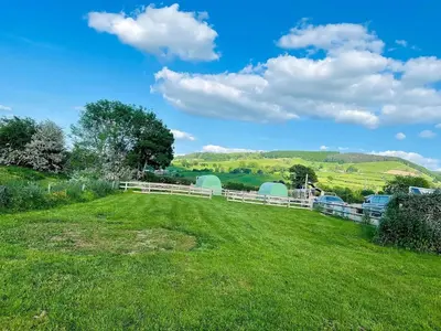 a white fence in a field with green grass at Green Dragon and Kitchen Pod - Sleeps 2 & Parking in Welshpool