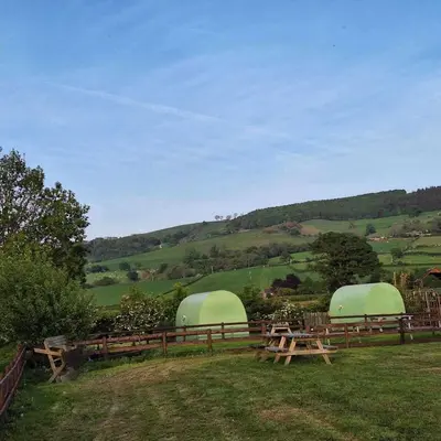 two green domes in a field with picnic tables at Green Dragon and Kitchen Pod - Sleeps 2 & Parking in Welshpool