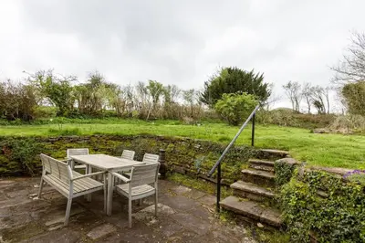 a table and chairs on a patio next to a field at 4 bedroom farmhouse Brecon Beacons in Talgarth