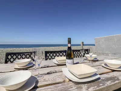 a table with a bottle of wine and plates on the beach at Glan Y Mor Borth in Aberystwyth