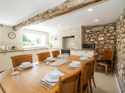 a kitchen and dining room with a wooden table and chairs at Pennal Cottage in Oswestry