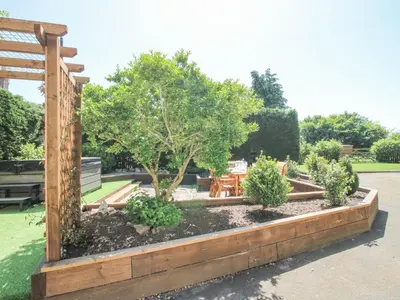 a garden with a bench and a table and trees at Pennal Cottage in Oswestry
