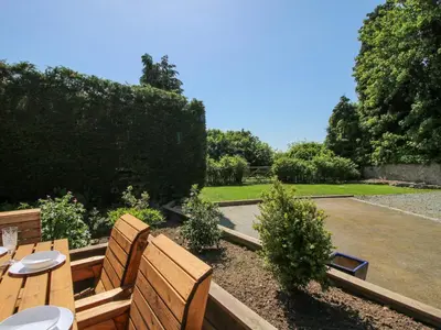 a garden with two wooden benches and a table at Pennal Cottage in Oswestry