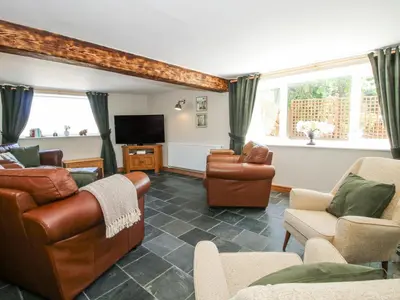 a living room with leather furniture and a flat screen tv at Pennal Cottage in Oswestry