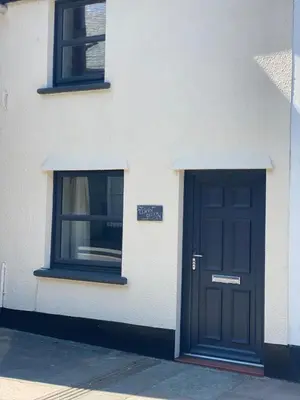 a white building with a black door and two windows at Llwyn Celyn 2 bedroom in Bala