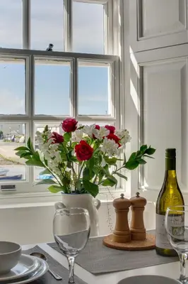 a table with a vase of flowers and a bottle of wine at 2 Bed in Aberaeron oc-bow173 in Aberaeron