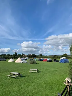 a group of tents in a field with two picnic tables at 5 Metre 'UNFURNISED' Bell Tent in Ball