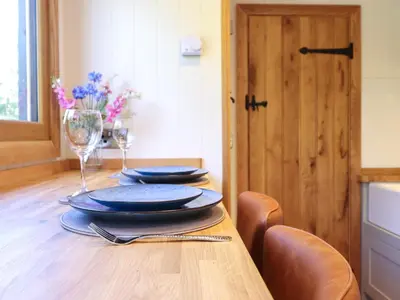 a wooden table with plates and wine glasses on it at Celyn in Dolgellau