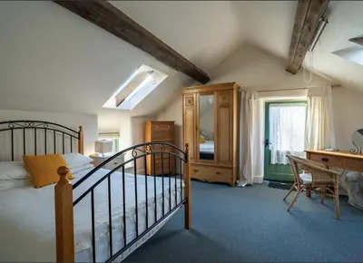 a bedroom with a bed and a dresser and a desk at Pretty barn conversion in seaside village in Llansantffraid