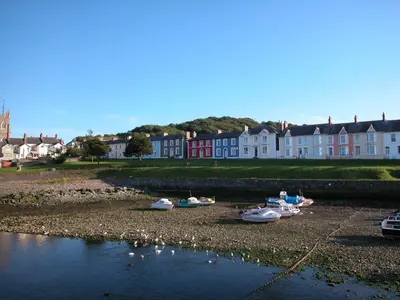a group of boats sitting on the shore of a river at Pretty barn conversion in seaside village in Llansantffraid