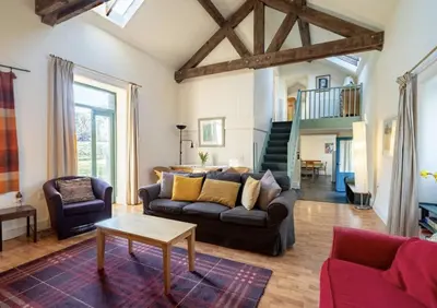 a living room with a couch and a table at Pretty barn conversion in seaside village in Llansantffraid