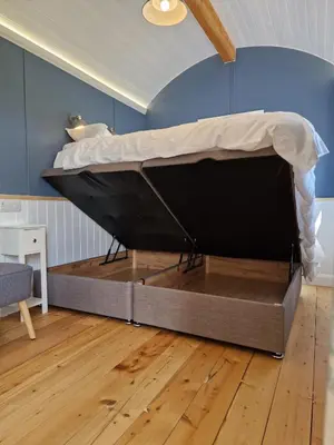 a bed sitting on a floor in a room at Oak Moor Shepherd Hut - Brecon Beacons, LD3 7TD in Tal-y-llyn