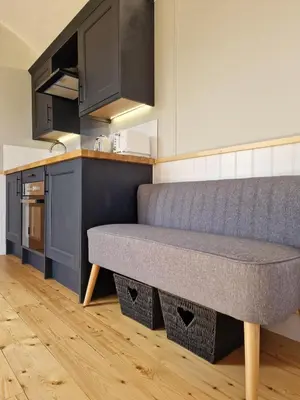 a kitchen with a couch in the middle of a room at Long Meadow Shepherd Hut - Brecon Beacons, LD3 7TD in Tal-y-llyn