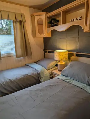 a bedroom with two beds and a table with a lamp at Aberystwyth holiday village walking distance to beach, town great outside space parking next to property in Aberystwyth