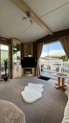 a living room with a couch and a tv and a table at Welsh Bayview Retreat 2-Bed Caravan & 2-Bed Chalet at Clarach Bay Holiday Village in Aberystwyth
