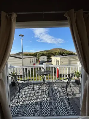 a patio with a table and chairs on a balcony at Welsh Bayview Retreat 2-Bed Caravan & 2-Bed Chalet at Clarach Bay Holiday Village in Aberystwyth