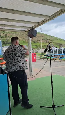 a man is standing in front of a microphone at Welsh Bayview Retreat 2-Bed Caravan & 2-Bed Chalet at Clarach Bay Holiday Village in Aberystwyth