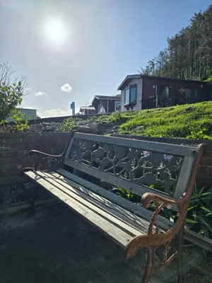 a wooden bench sitting next to a brick wall at Welsh Bayview Retreat 2-Bed Caravan & 2-Bed Chalet at Clarach Bay Holiday Village in Aberystwyth