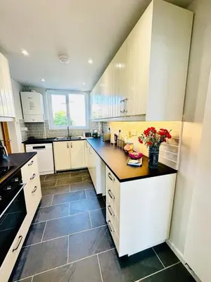 a kitchen with white cabinets and a black counter top at Ynyslas View in Aberdyfi