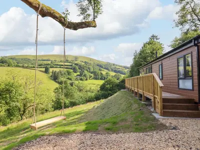 a tiny house with a porch and swings at The Owlet in Llanidloes