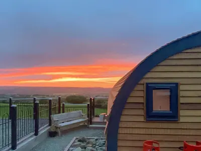a building with a bench and a sunset in the background at Luna Holiday Pod - Uk48590 in Church Stretton