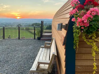a wooden bench sitting on the side of a building with flowers at Luna Holiday Pod - Uk48590 in Church Stretton