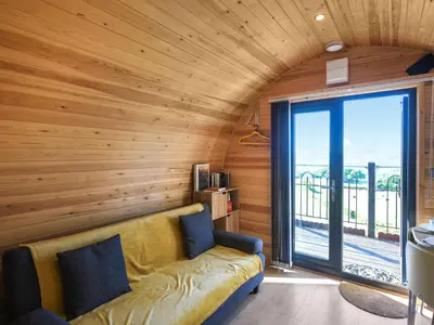 a living room with a couch and a large window at Sunset Holiday Pod - Uk48592 in Church Stretton