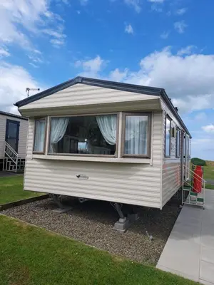 a white caravan with a large window on a yard at 63 Bardsey View Holiday Park in Mydroilin