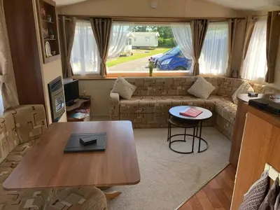 a living room with a table and a couch at 63 Bardsey View Holiday Park in Mydroilin