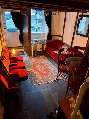 a living room with a red couch and a table at The Little Laura Ashley House in Machynlleth