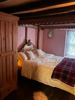 a bedroom with a large bed with a wooden canopy at The Little Laura Ashley House in Machynlleth