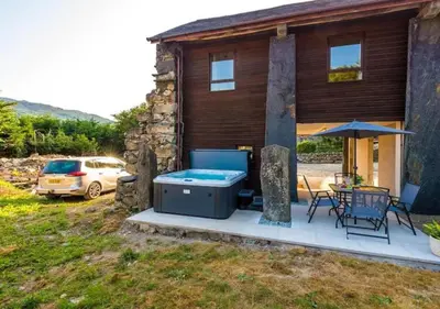 a house with a hot tub and a table and chairs at Peaceful Barn Near Cader Idris in Dolgellau