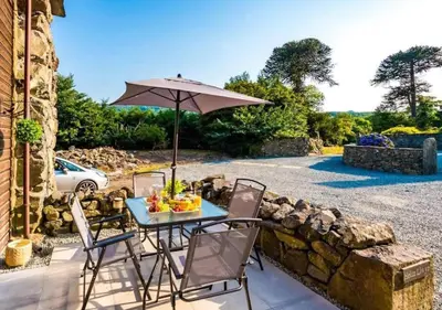a table and chairs with an umbrella on a patio at Peaceful Barn Near Cader Idris in Dolgellau