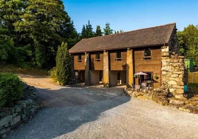 a large wooden barn with a gravel driveway at Peaceful Barn Near Cader Idris in Dolgellau