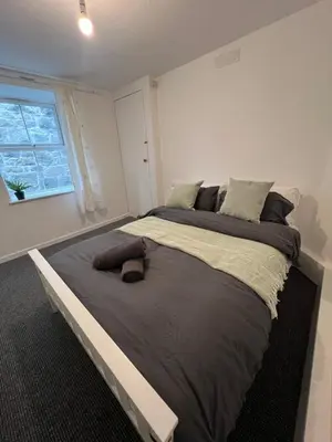 a large bed in a white room with a window at Cosy Cader Cottage in Dolgellau