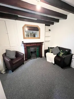 a living room with two chairs and a fireplace at Cosy Cader Cottage in Dolgellau