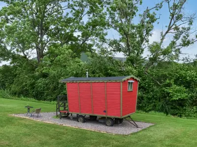 a red shed sitting in a park with a bench at Tilly - Uk49798 in Brecon