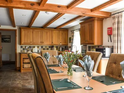 a kitchen with a wooden table with chairs and a dining room at Priory Cottage in Clifford