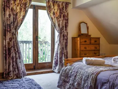 a bedroom with a bed and a large window at Priory Cottage in Clifford
