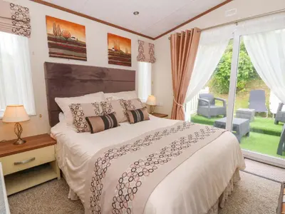 a bedroom with a large bed and a large window at Ty Seren in New Quay