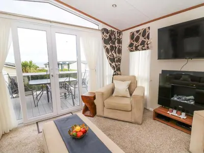 a living room with a television and a chair and a table at Ty Seren in New Quay